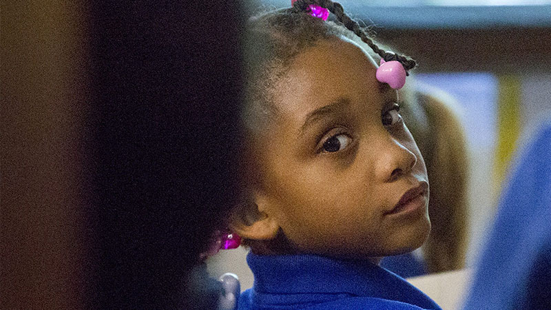 A young Baltimore City School girl looks over her shoulder at the camera