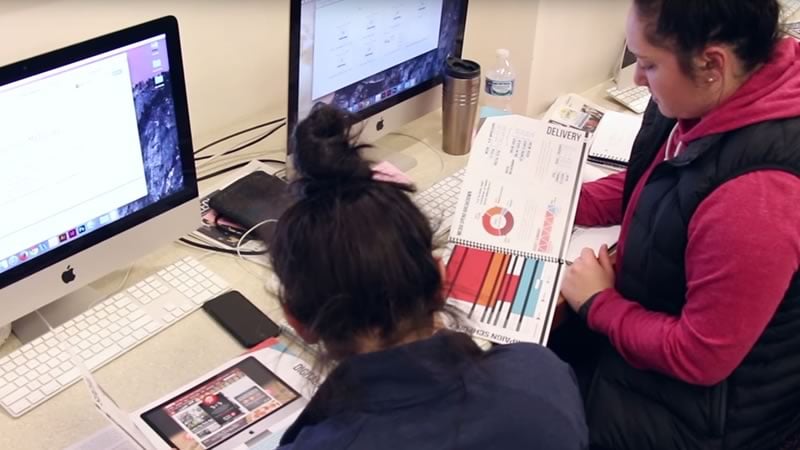 Two students review a statistial report as part of COMM 425 Advanced Advertising Campaigns