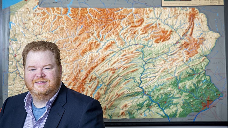 Erik Arneson, executive director of the Pennsylvania Office of Open Records, poses in his offices in front of a large map of Pennsylvania.