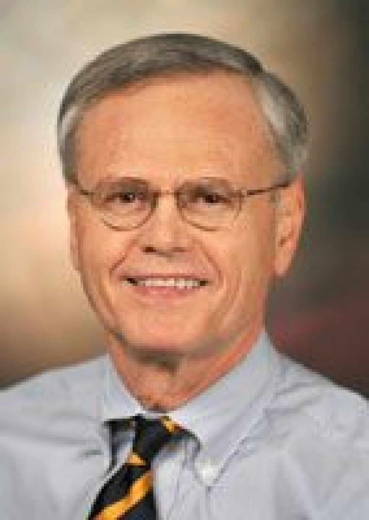 Smiling man in glasses, shirt and tie.