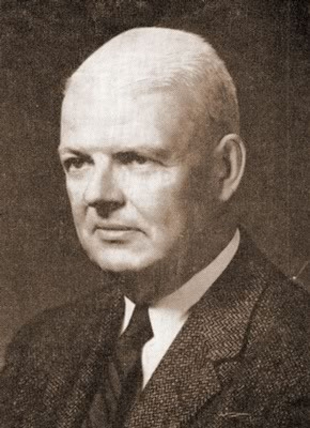 Black-and-white photo of balding main in coat and tie.