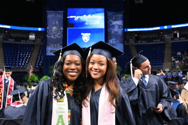 Two graduates side-by-side in caps and gowns.