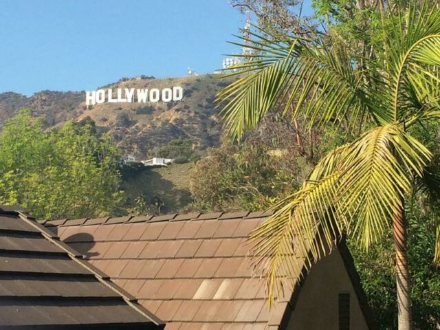 Photo of the iconic Hollywood sign in the background shot over an apartment building roof.