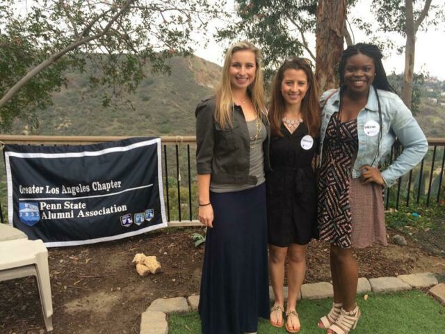 Three young female students stand in front of a flag that reads Penn State Alumni Association, Greater Los Angeles Chapter