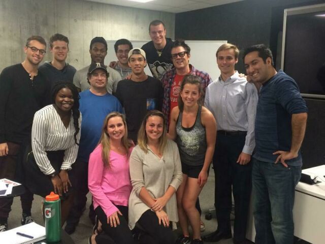 A dozen students pose for a photo with actor Johnny Knoxville and writer/producer Ricky Blitt