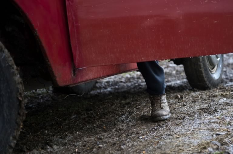 Zack's pant leg and boot visible under the open door of his truck.