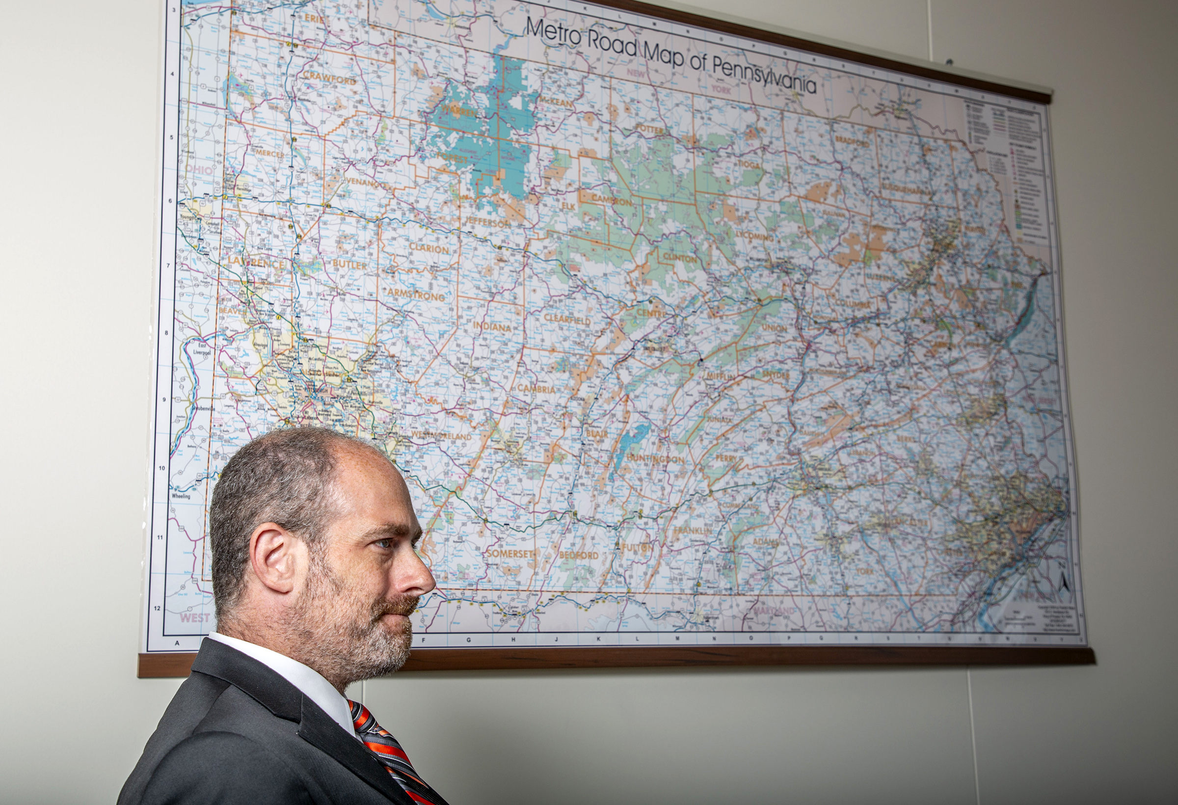 Nathan Byerly, OOR deputy director poses in front of a large map of Pennsylvania.