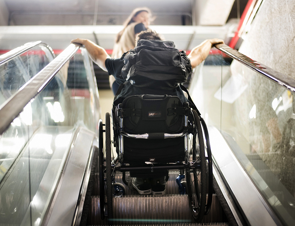 Brett Gravatt rides an escalator in his wheelchair.